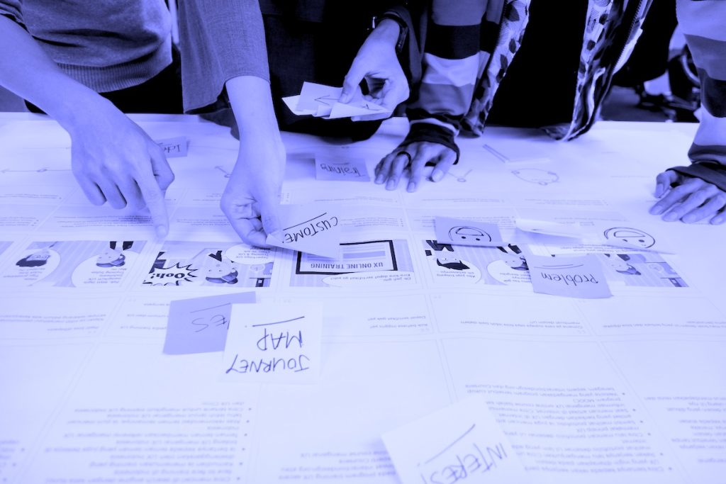 Drawing in Diversity Workshop with participants crowded around a table, using drawing and ideation materials to brainstorm ideas
